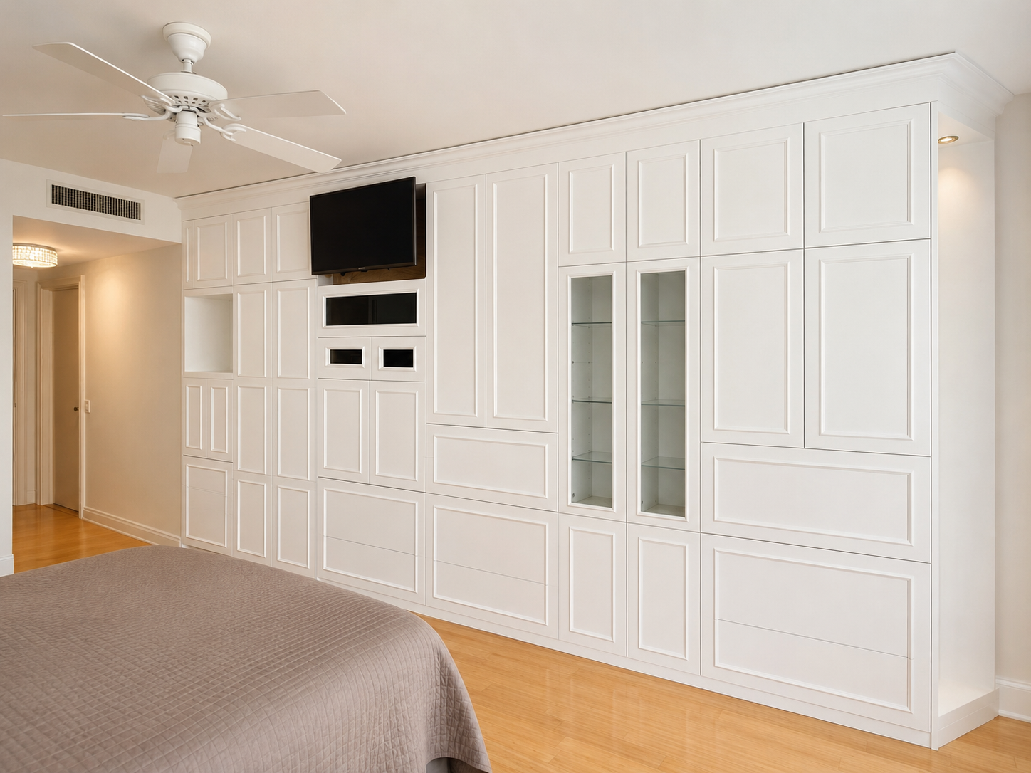 White painted wall unit with recessed panel doors, drawers, glass-front display cabinet, and TV niche