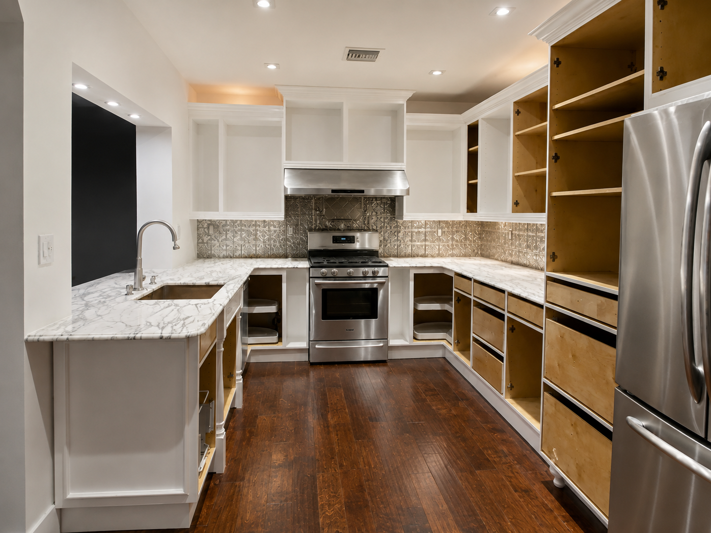 Kitchen mid-installation with painted white face frames, marble countertops, and cabinet boxes awaiting doors
