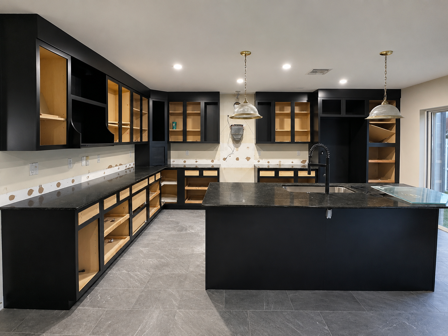 Black kitchen cabinetry during installation, with boxes and drawer bases set before doors and fronts are hung
