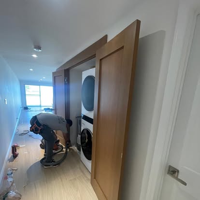 Custom natural wood doors and casing being fitted in an interior hallway