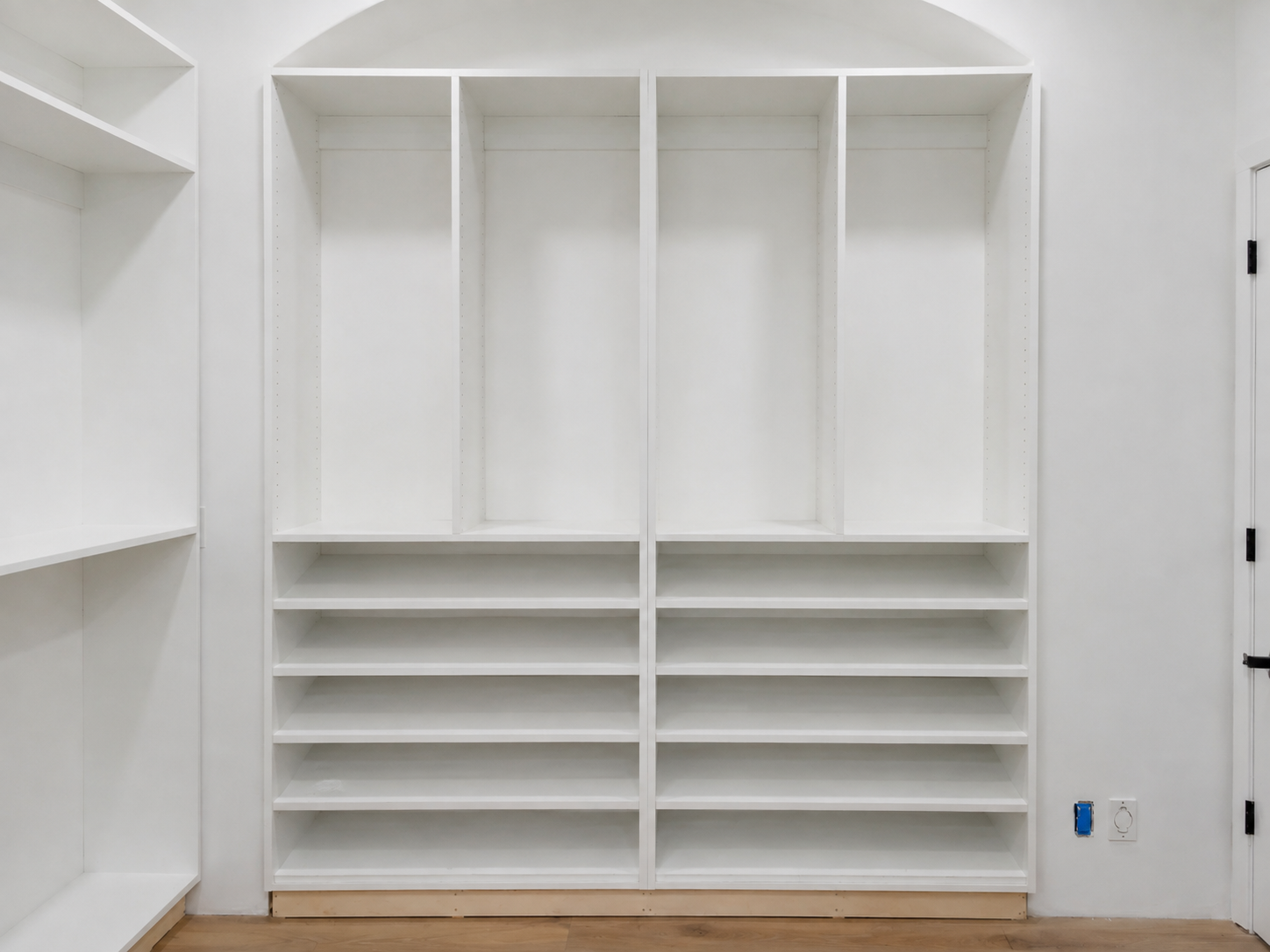 White closet built-in under an arched niche with hanging bays and shoe shelves