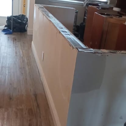 A woodworker assembling the base of a custom cabinet unit during a work-in-progress install