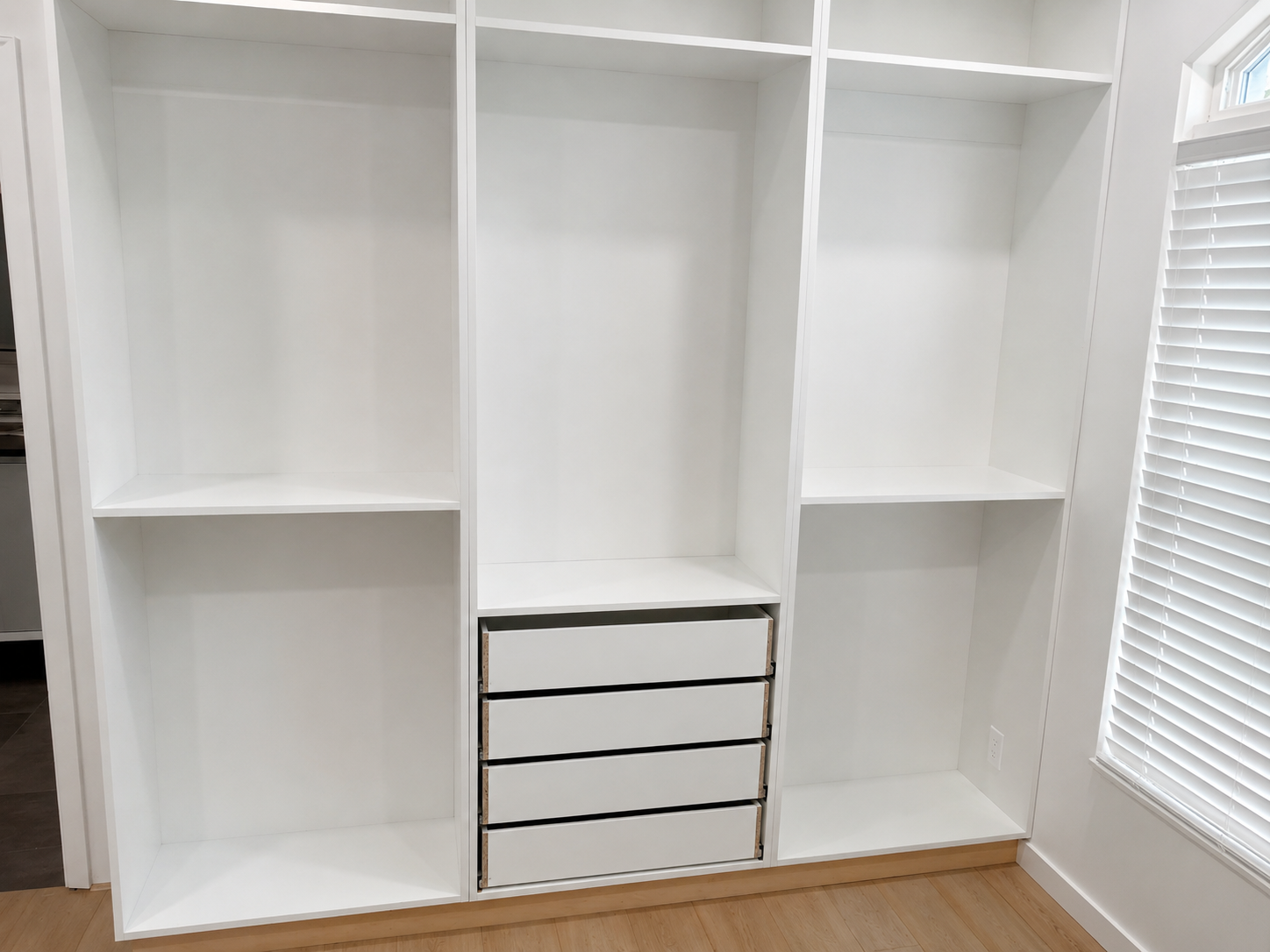 White closet built-in with three bays and four drawers awaiting fronts
