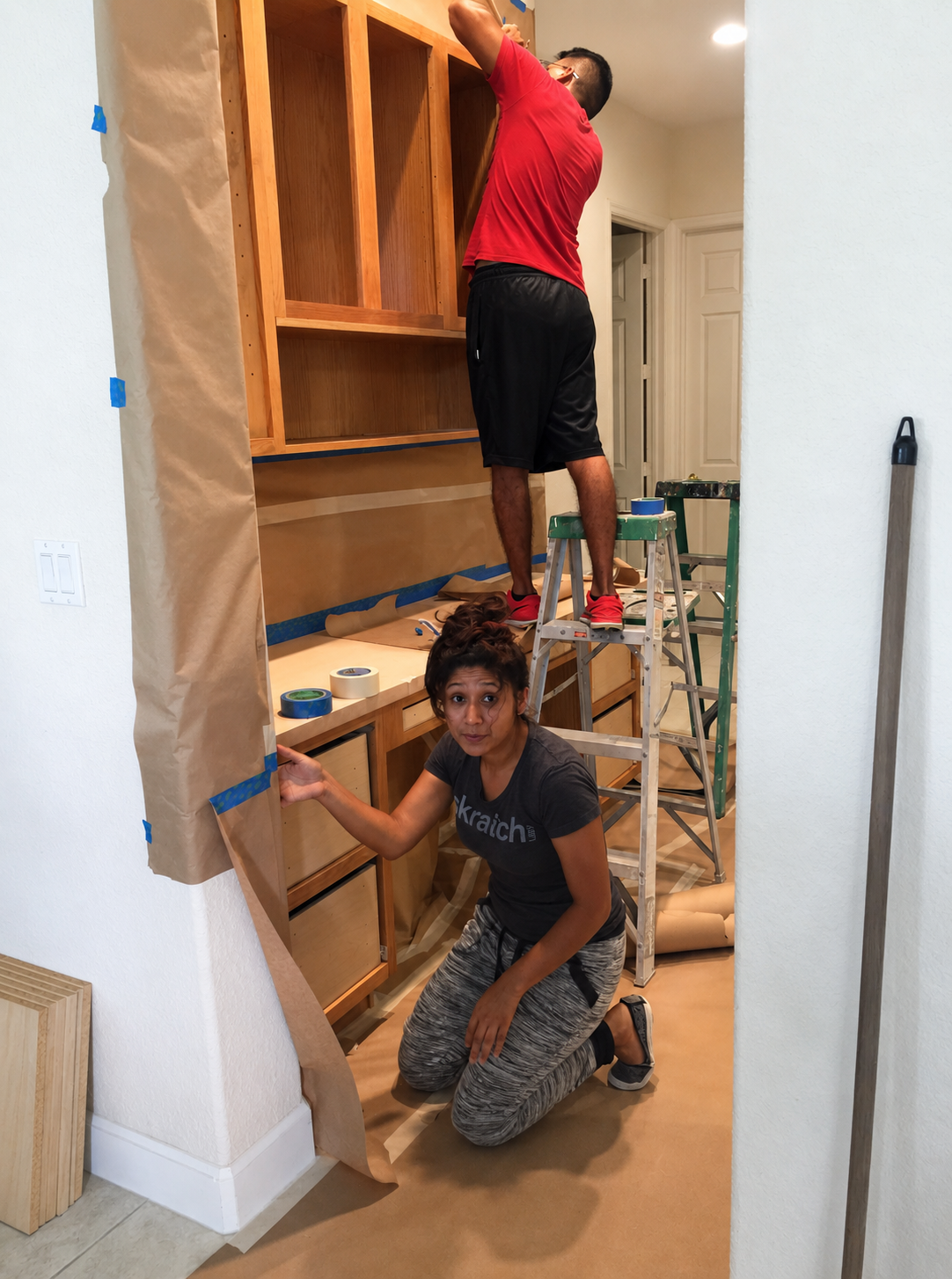 Two CQ Woodworking team members masking and papering a cabinet run before finishing